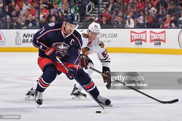 Nick Foligno of the Columbus Blue Jackets skates the puck away from Brandon Mashinter of the Chicago Blackhawks during the second period of a game on...