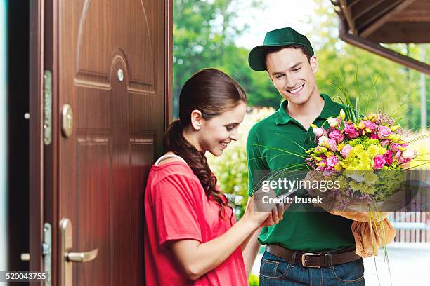 young delivery man delivering flowers - flower delivery stock pictures, royalty-free photos & images