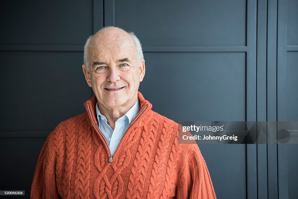 Senior man smiling, wearing orange sweater