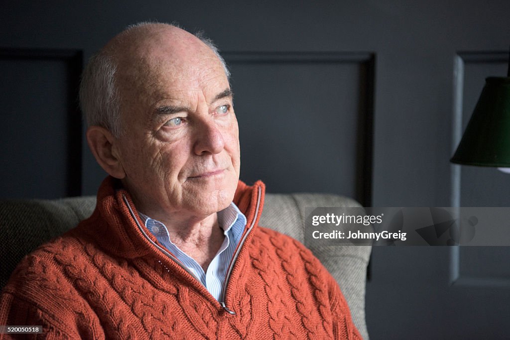 Senior man wearing orange sweater looking away