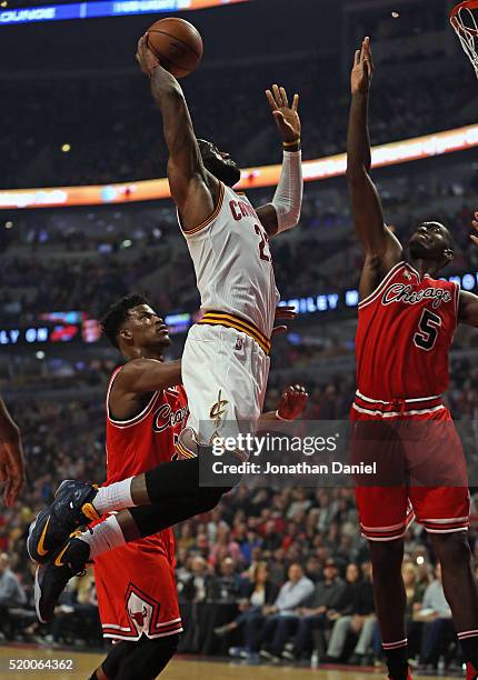 LeBron James of the Cleveland Cavaliers goes up for a dunk over Jimmy Butler and Bobby Portis of the Chicago Bulls at the United Center on April 9,...