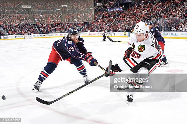 Brandon Mashinter of the Chicago Blackhawks passes the puck away from David Savard of the Columbus Blue Jackets during the third period of a game on...