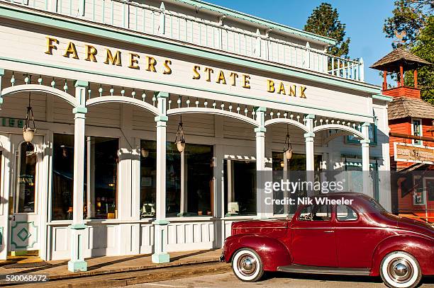 An antique vintage automobile, participating in the annual Auto Rally event, stands in front of an historic bank building on Main Street in the...