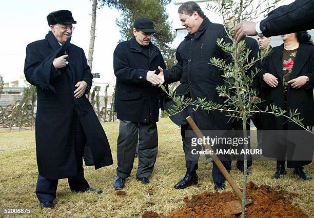 Palestinian leader Mahmud Abbas smiles after planting a tree next to the grave site of late Palestinian leader Yasser Arafat as PLO official Yasser...