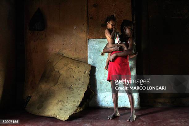 Onesime stands with her son in the bedroom of the house she shares with 26 other family members in Port Louis, Mauritius, 17 January 2005. The...