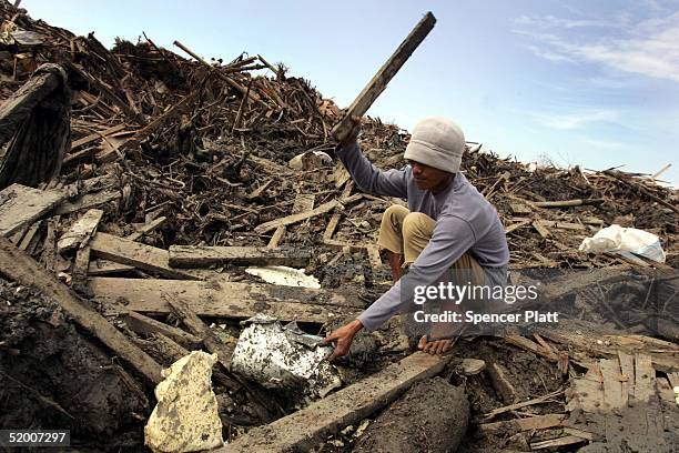 Boy hammers at a metal pot scavenged in the remains of tsunami damaged homes January 18, 2005 in Banda Aceh, Indonesia. Thousands of residents are...