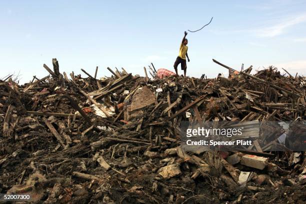 Boy throws a piece of wire scavenged in the remains of tsunami damaged homes January 18, 2005 in Banda Aceh, Indonesia. Thousands of residents are...