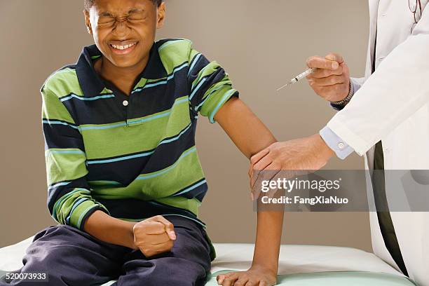 teenage boy (12-13) bracing himself for injection - sewing needle stock pictures, royalty-free photos & images