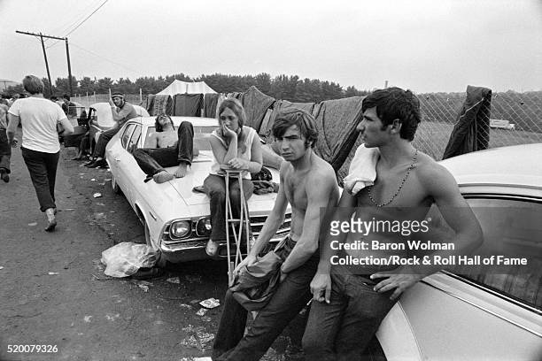 Group of visitors lean on the cars to rest at the Woodstock Music & Art Fair celebrated in Bethel, NY, August 15, 1969.