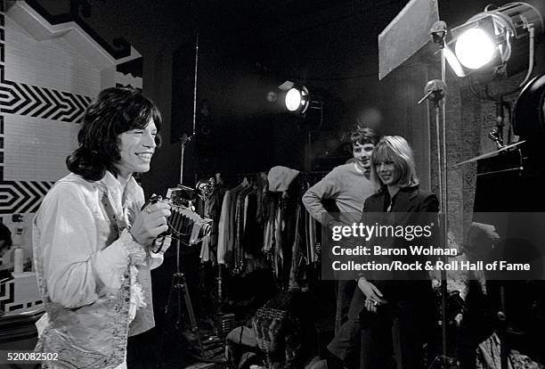 Rolling Stones' Mick Jagger takes a photograph on the set of 'Performance' with Anita Pallenberg in the background, Shepperton Studios, London,...