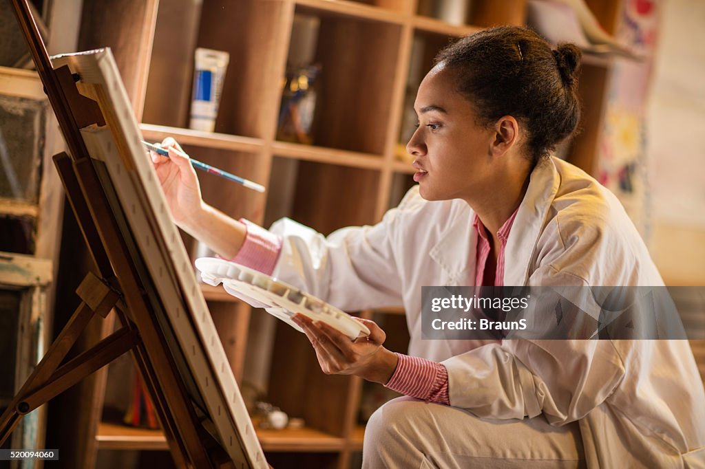 Young African American painter working in her studio.