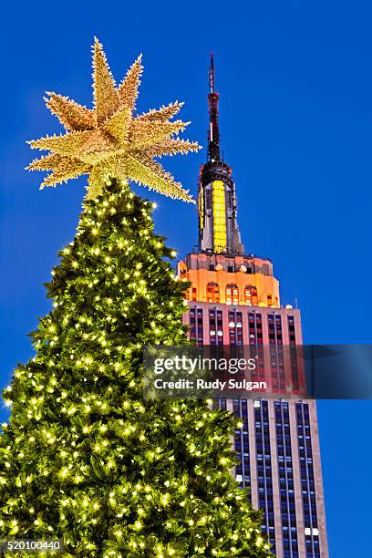 christmas tree with the empire state building behind it, new york city - new york city christmas stock pictures, royalty-free photos & images