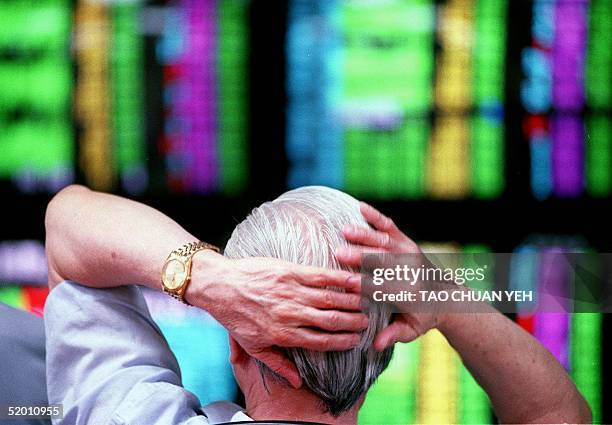 Man sits in front of a wall of computer screens showing volatile trading in Taiwan's stock market 19 July 1999. The index rose 0.3 percent, or 20.66...