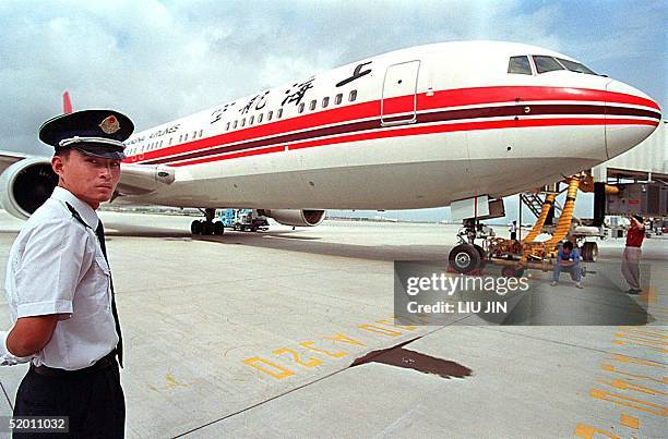 An airport policeman stands by a Shanghai Airlines airplane during the opening of Shanghai's new Pudong International Airport, 16 September 1999....
