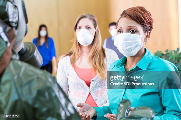 businesspeople wearing protective masks talking with person in hazmat suit - ebola crisis stock pictures, royalty-free photos & images