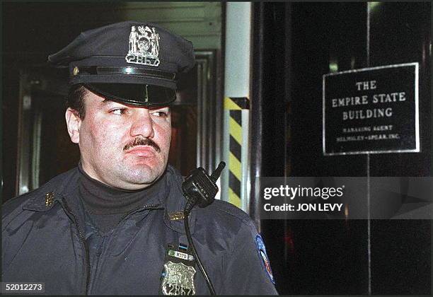 New York City police officer stands guard at the door of the Empire State Building 23 February in New York after a gunman openned fire on the 86th...