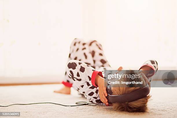 kleine junge in pyjamas hören die musik im kopfhörer - children music stock-fotos und bilder