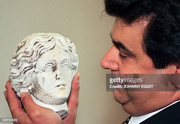 An official at the Turkish embassy with one of the Greco-Roman marbles after it was handed back to the Turkish Ambassador Ozdem Sanberk, at a...