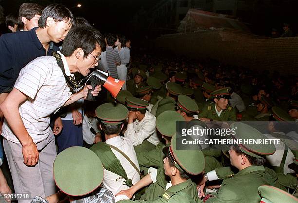 Using a loudspeaker, a student asks soldiers to go back home as crowds flooded into the central Beijing 03 June 1989. On the night of 03 and 04 June...