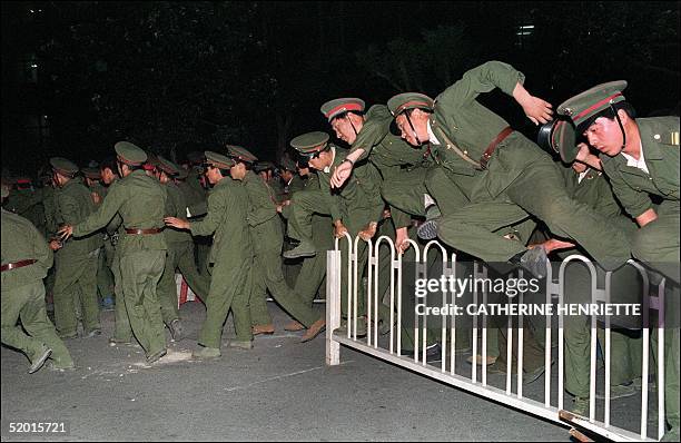 People Liberation Army soldiers leap over a barrier on Tiananmen Square in central Beijing 04 June 1989 during heavy clashes with people and...