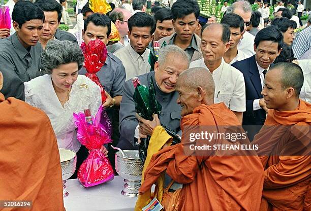 Prince Norodom Sihanouk and his wife Princess Monique offer the food to a group of monks 15 November 1991 during a Buddhist ceremony in a Phnom Penh...