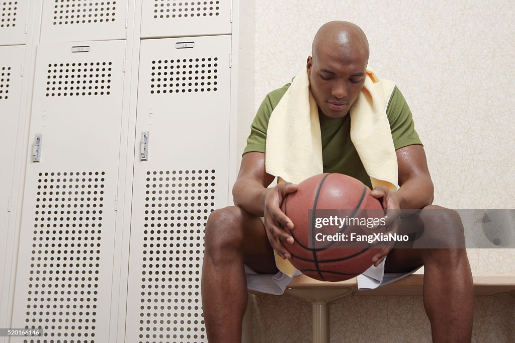 Hombre con una pelota de baloncesto en un vestuario