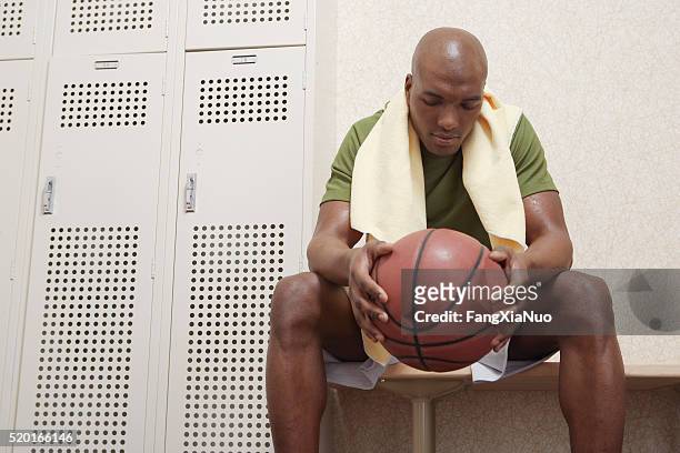 man with a basketball in a locker room - forward athlete stock pictures, royalty-free photos & images