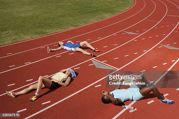 corredores agotados en pista - competición por equipos fotografías e imágenes de stock