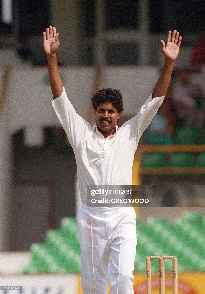 Indian bowler Kapil Dev raises his arms after taki