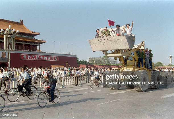 Beijing workers sitting in a bulldozer shovel shout slogans as they drive their engine in front of the Forbidden City in Tiananmen Square 25 May 1989...