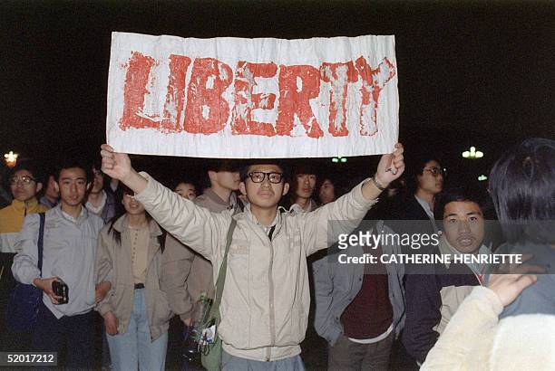 Student displays a banner with one of the slogans chanted by the crowd of some 200,000 pouring into Tiananmen Square 22 April 1989 in Beijing in an...