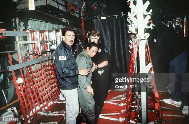 In this photo released 04 January 1990 by the Defense Department, Panamian General Manuel Noriega is brought on board a US military plane 3 January...