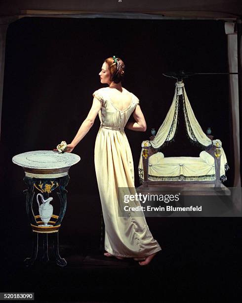 Model in Empire setting wearing ivory-colored nightdress with decollete neckline, ribbon-drawn waistline by Iris.