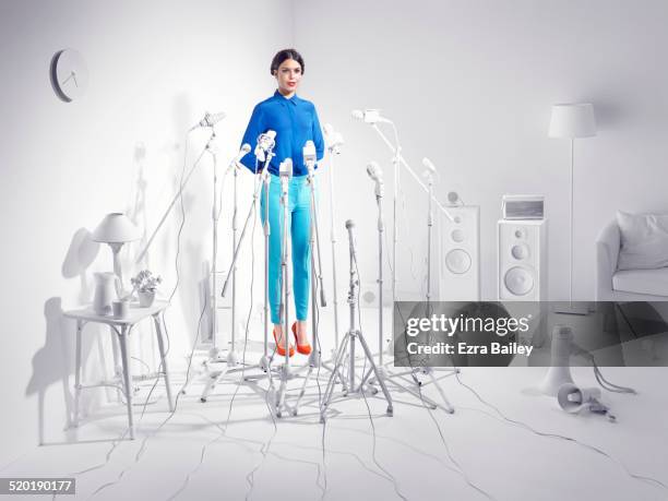 woman standing in a room of white microphones. - colour microphone stock-fotos und bilder