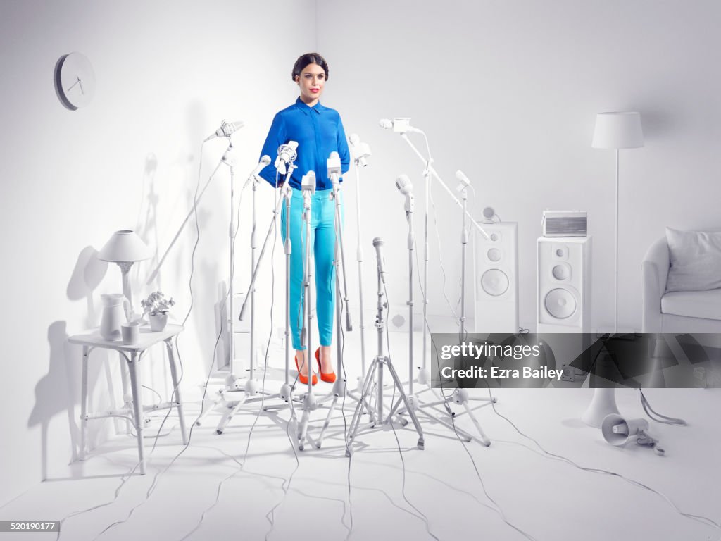 Woman standing in a room of white microphones.