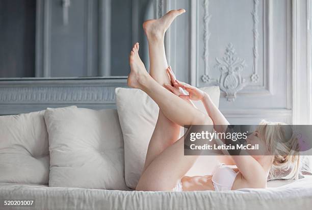 woman in underwear with legs and arms up on a sofa - donne bionde scalze foto e immagini stock