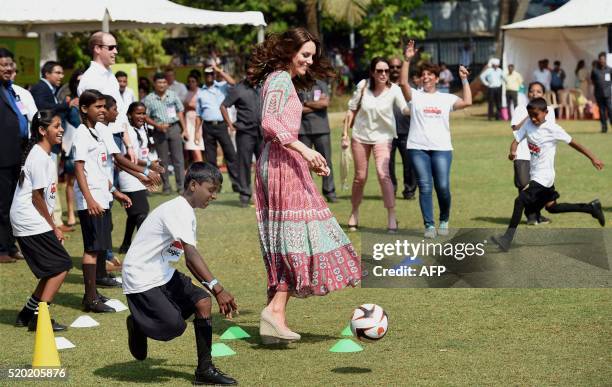 Catherine, Duchess of Cambridge is watched by Prince William, Duke of Cambridge as she takes part in games with Indian children who are beneficiaries...