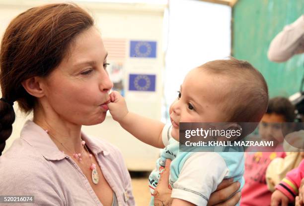 Actress and United Nations Population Fund's Goodwill Ambassador, Ashley Judd , carries a Syrian child during a visit at the Zaatari refugee camp,...