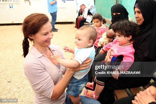 Actress and United Nations Population Fund's Goodwill Ambassador, Ashley Judd , carries a Syrian child during a visit at the Zaatari refugee camp,...