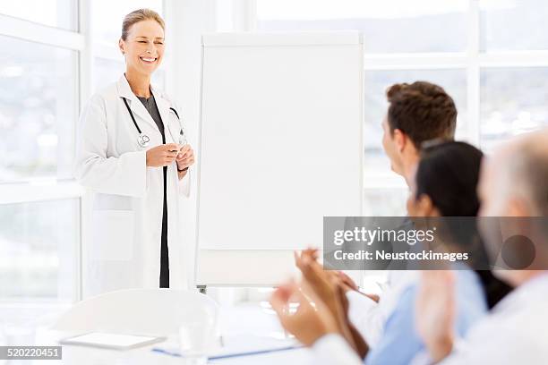 doctor looking at medical team clapping for her - applauding nurses stock pictures, royalty-free photos & images