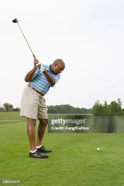 golfer swinging to hit ball on golf course - male golfer stock pictures, royalty-free photos & images