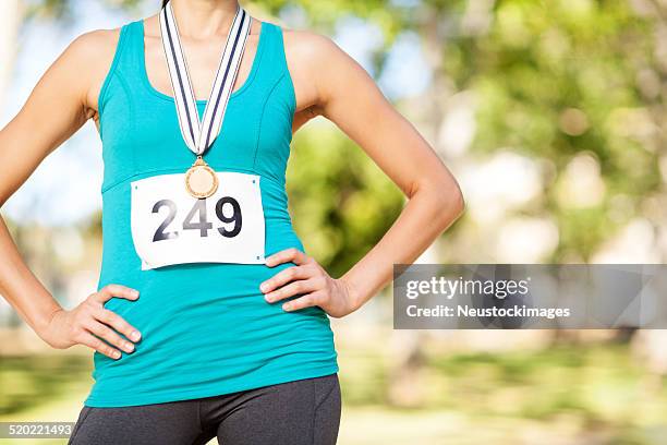 marathon gold medalist standing with arms akimbo at park - marathon medal stock pictures, royalty-free photos & images