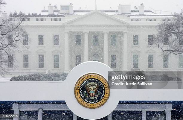 The presidential seal affixed to the top of the Inaugural viewing stand is seen in front of the White House during snow flurries January 19, 2005 in...