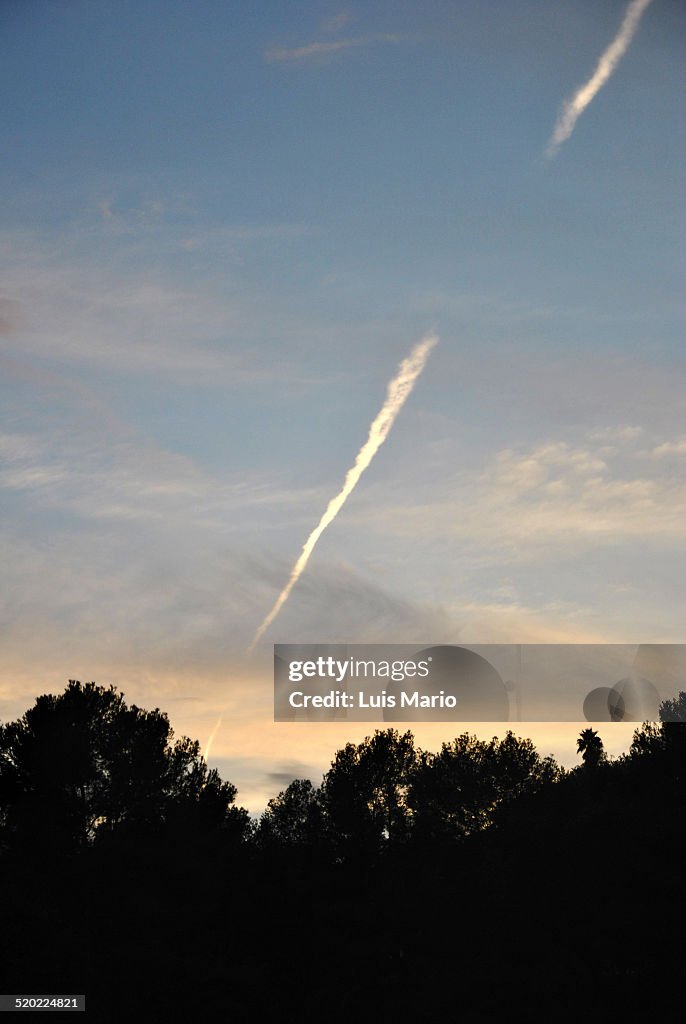 Sunset with cloudy sky and smoke trail