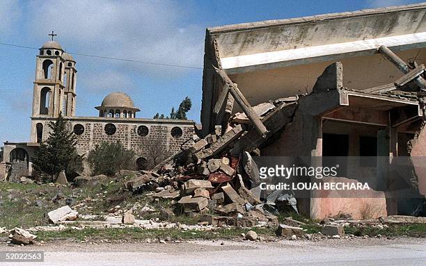 The Saint George Greek Orthodox church appears 02 August 1999 behind the ruins of a building destroyed in the village of Kuneitra on the Golan...