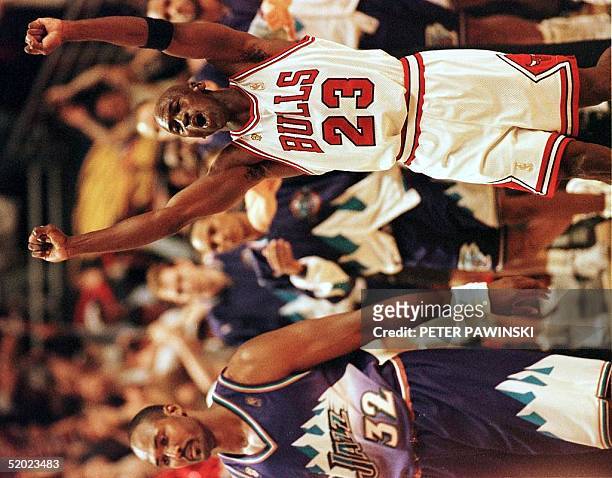 Michael Jordan of the Chicago Bulls jumps in the air as Karl Malone of the Utah Jazz walks off the court 13 June after game six of the 1997 NBA...