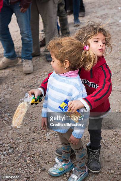 refugee sisters in breakfast line in chios refugee camp - quiosque stock pictures, royalty-free photos & images