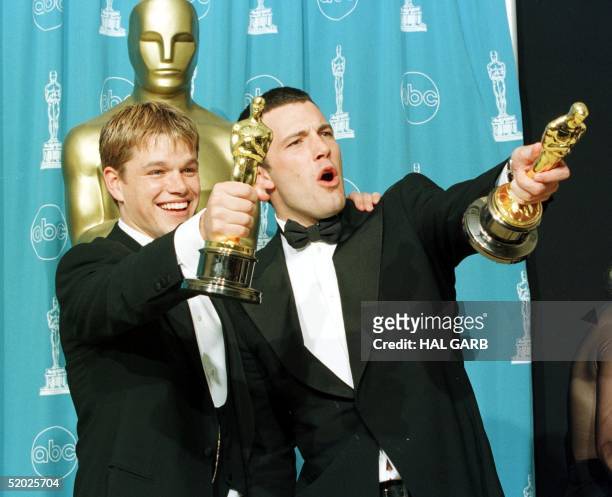 Oscar winners Matt Damon and Ben Affleck hold the awards they won for best original screenplay for the film "Good Will Hunting" which the two wrote...