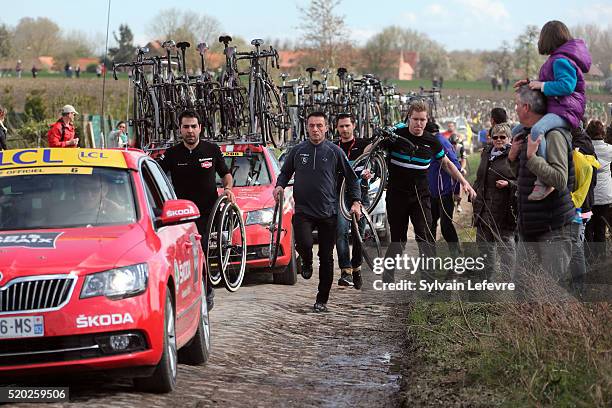 Teams members run to fix bicycles after massive crash on Mons-en-Pevele cobble-stoned section during 2016 Paris-Roubaix Race on April 10, 2016 in...