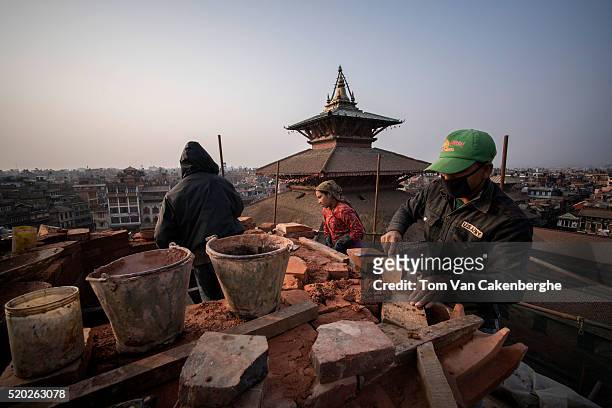 Construction workers, experienced in traditional Nepali style architecture, are standing on a scaffold and rebuild the top of the major Taleju temple...